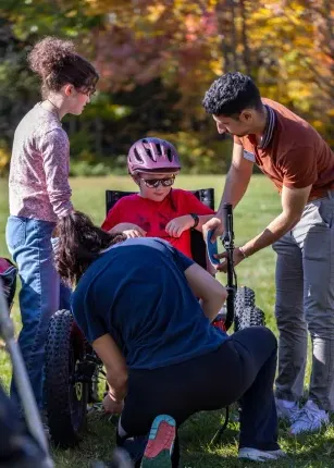 UNE volunteers assist a power soccer player outside