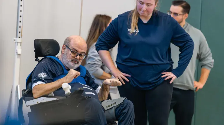 A UNE student assists a wheelchair user at the power soccer demo