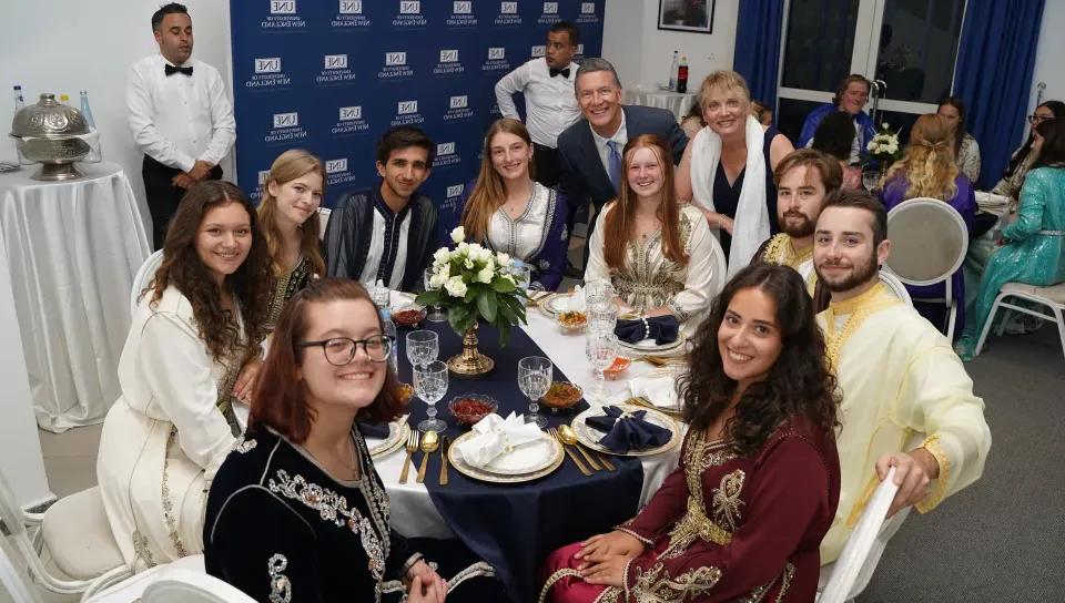 UNE students pose for a photo around a dinner table